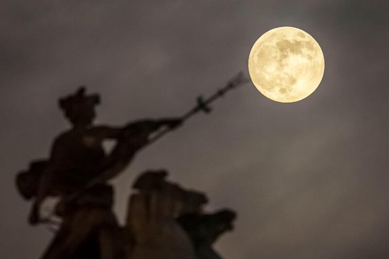 A super moon rises above the 'Maritime Prowess' by Albert Hemstock Hodge on the Guild Hall ahead of the Lunar Eclipse, in Hull, England. PA via AP