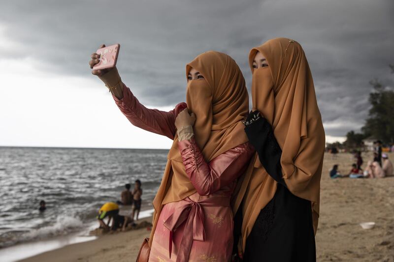 Women take a selfie on the Talo Kapo beach while marking Eid Al Fitr in Pattani, Thailand.