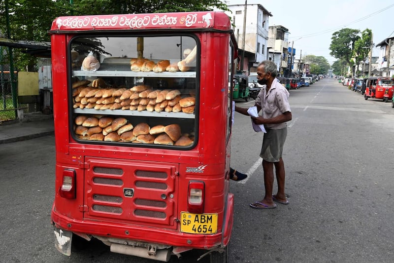 A man buys bread from a vendor on a street in Colombo after a three-day curfew was announced to contain the spread of the Covid-19 coronavirus. AFP