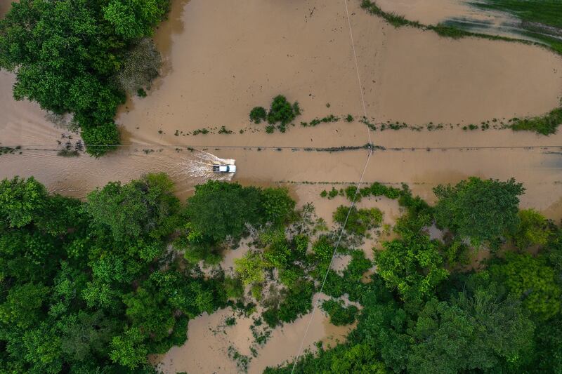 A vehicle drives along the flooded Wolverine Road in Breathitt County, Kentucky. AP