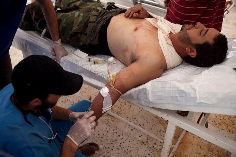 epa02927307 An injured Libyan rebel fighter is assisted by doctors at a field hospital  near Sirte as rebels push to take control of the city, in Libya, on 20 September 2011. Reports state on 20 September 2011 that the new Libyan leadership was recognized at a formal meeting at the United Nations (UN), where the new red, black and green flag of rebel fighters was raised alongside that of the UN. Close to 60 government representatives, including 21 heads of state, attended the meeting to pursue talks on assisting Libya in reconstruction efforts and the establishment of democratic institutions.  EPA/GUILLEM VALLE *** Local Caption ***  02927307.jpg