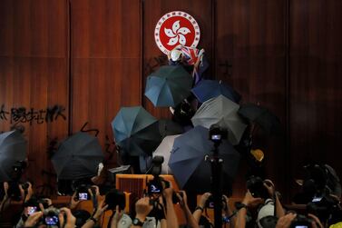A protester covers the Hong Kong emblem with a Hong Kong colonial flag after they broke into the Legislative Council building in Hong Kong. AP