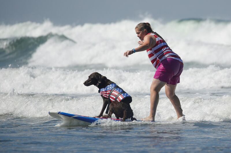 A woman surfs with her dog as she competes in the 14th annual Helen Woodward Animal Center "Surf-A-Thon". Reuters