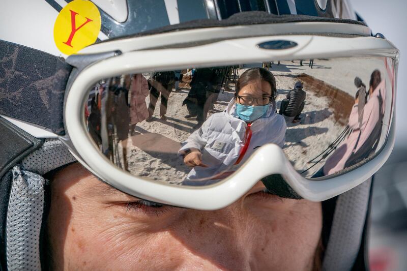 A staff member wearing a face maskis reflected in the goggles of a skier at the National Alpine Skiing Center in Yanqing on the outskirts of Beijing. Beijing Olympic organisers showed off the downhill skiing venue and the world's longest bobsled and luge track Friday, one year ahead of the scheduled opening of the 2022 Olympic Winter Games. AP Photo