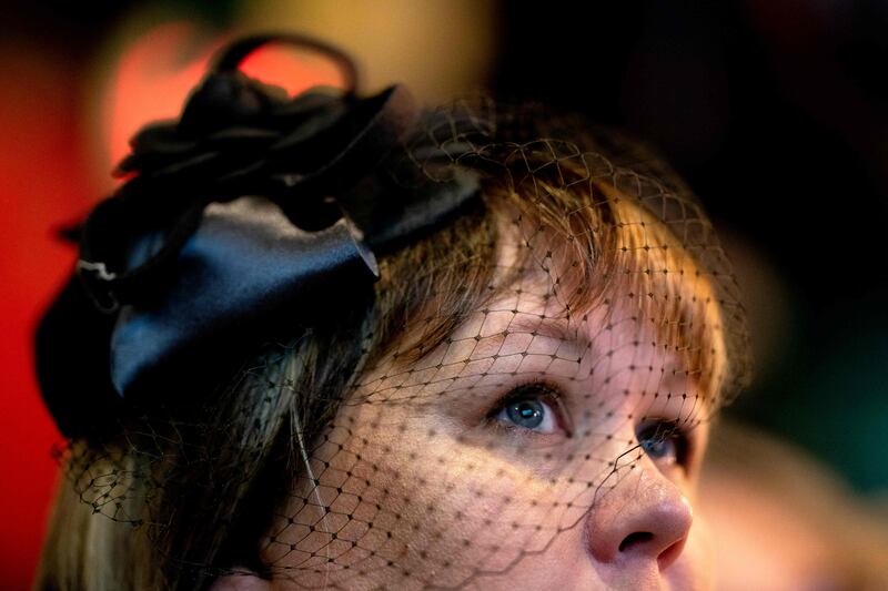 A person wears a mourning headdress while watching the state funeral at The Queen Vic pub. AFP