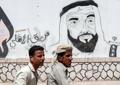 A picture taken on August 8, 2018 during a trip in Yemen organised by the UAE's National Media Council (NMC) shows Yemeni men riding in a motorcycle past a mural depicting the late UAE founder and president Sheikh Zayed bin Sultan al-Nahyan, along a street in the southeastern port city of Mukalla, the capital Hadramawt province. (Photo by KARIM SAHIB / AFP)