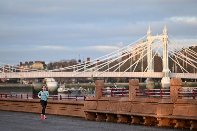 A person jogs along the river front at sunrise as they exercise in Battersea Park in London on January 17, 2021, as surging cases of the novel coronavirus are placing health services under increasing pressure. Britain recorded another 55,761 cases of coronavirus on Friday, although new cases have fallen nearly 14 percent in the last week. / AFP / Justin TALLIS
