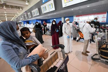 A passenger carries her child as they wait to check in at Dubai International Airport. AFP