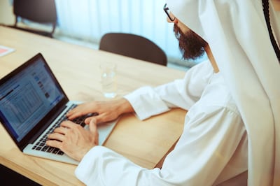 TWJRJ2 Arab saudi businessman working online with a laptop and tablet in his comfortable cabinet or office. Male model as an enterpreneur. Concept of business, finance, modern technologies, start up, economy.