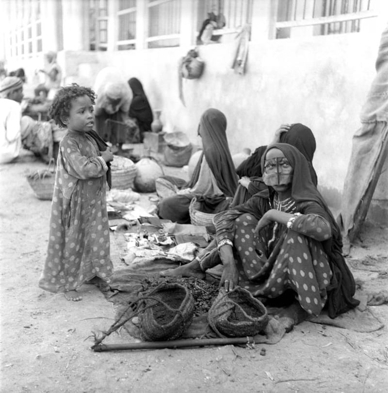 Selling charcoal in Dubai in 1949, a woman sits with other market vendors accompanied by a young girl. Courtesy Ronald Codrai / TCA Abu Dhabi