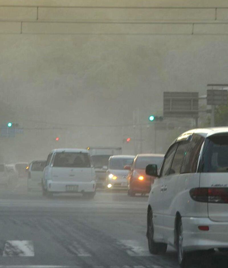 In this Sunday, Aug. 18, 2013 photo, drivers use headlights early evening as the streets are covered by ash after the Sakurajima volcano erupted earlier in the day in Kagoshima, on the southern Japanese main island of Kyushu. People in the city wore masks and raincoats and used umbrellas to shield themselves from the ash after the eruption. (AP Photo/Kyodo News) JAPAN OUT, MANDATORY CREDIT *** Local Caption ***  Japan Volcano.JPEG-0b64d.jpg