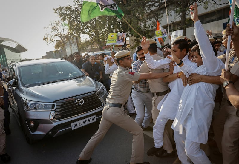 A police officer pushes supporters of Congress leader Rahul Gandhi at New Delhi airport as he leaves in his car. Reuters