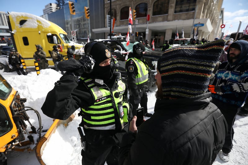 A man stands in front of a police officer as lorry drivers and supporters continue to protest against Covid-19 vaccine mandates, in Ottawa, Canada. Reuters