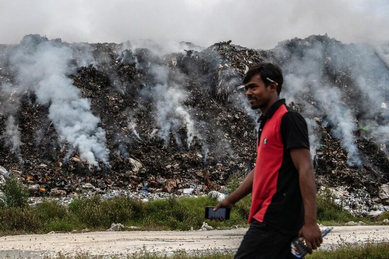 MALE, MALDIVES - DECEMBER 11: A man walks past burning rubbish at a landfill site on the artificial island of Thilafushi on December 11, 2019 near Male, Maldives. The site receives approximately 300 tonnes of rubbish each day mostly from the capital Male and has been criticised for its failure to recycle and properly process waste. The Maldives is the worlds lowest lying country with a highest natural point of just 2.4 meters above sea level. As well as an increasing population, the nation faces a number of problems caused by climate change including rising sea levels, unpredictable weather, a shortage of drinking water, coastal erosion and declining fish stocks. With no rivers or streams on any of the islands, Maldivians have traditionally lived from fishing and except for Male and a handful of other islands, most islands rely on rain for drinking water and, increasingly, bottled water brought in from other islands. (Photo by Carl Court/Getty Images)