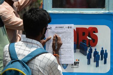 An unemployed youth fills an application form to access job openings in the private sector outside an 'employment van' in Hyderabad. AFP