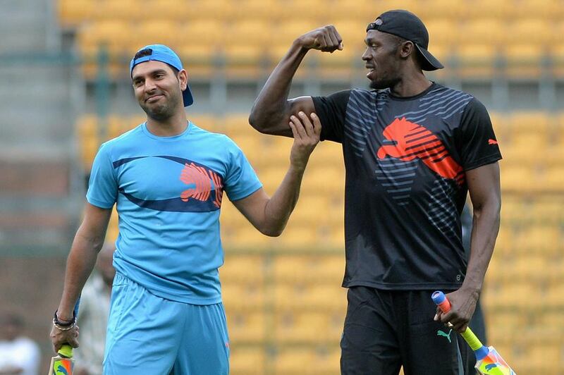 Usain Bolt flexes for Yuvraj Singh following a six during a practice session on Tuesday before their exhibition four-over cricket match. Bolt, on his first visit to India, took part in the match with some of India's top players. Manjunath Kiran / AFP