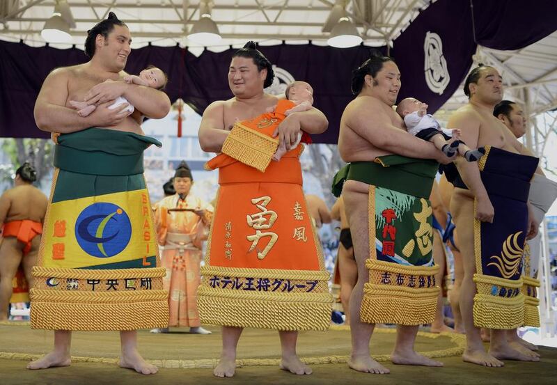 Sumo wrestlers hold babies before the 'Honozumo', a ceremonial sumo tournament at the Yasukuni Shrine precincts, in Tokyo, Japan, on Friday. Thousands of spectators enjoyed this one-day event where sumo wrestlers perform their skills. Franck Robichon / EPA / April 4, 2014 