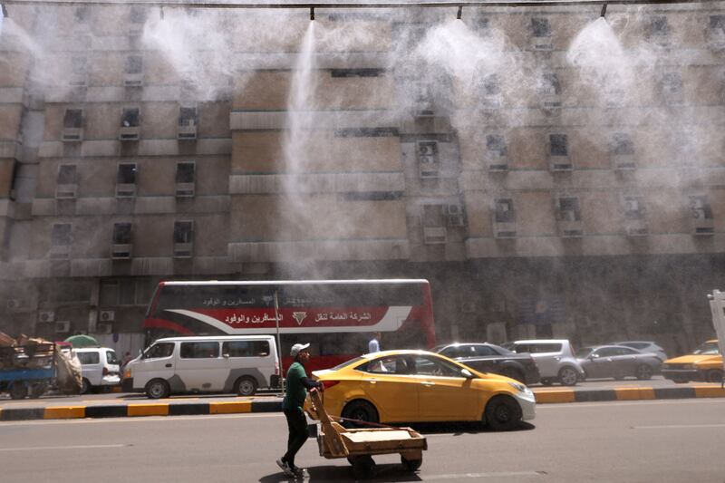 Water-spraying fans on the streets of Baghdad on June 11. Many Iraqis attribute electricity shortages to corruption, as well as years of conflict. AFP