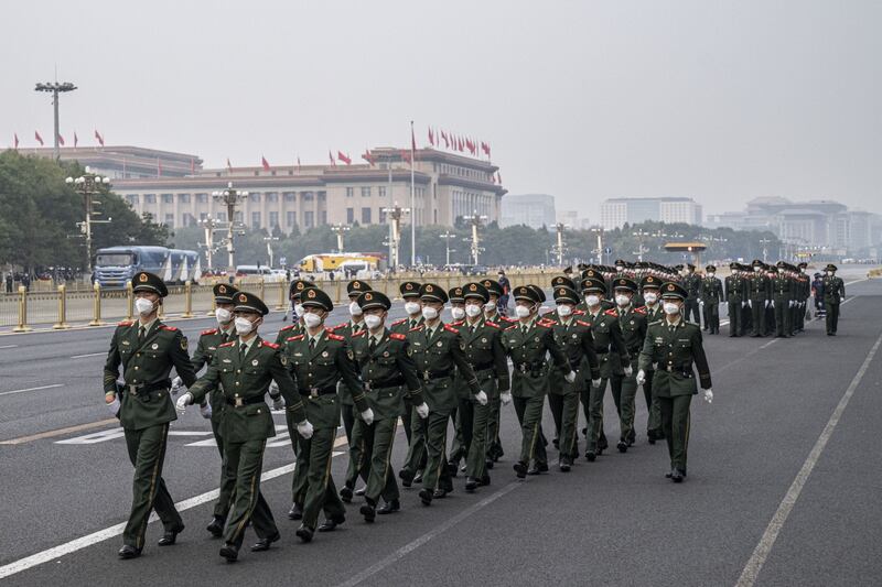 Masked soldiers of the People's Liberation Army march in Beijing after completing a flag-raising ceremony to mark 73rd National Day. Bloomberg