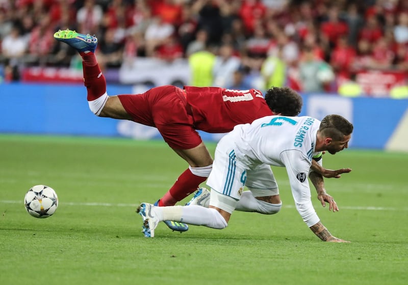 Salah heads for the ground as Ramos tugs at his arm. Armando Babani / EPA