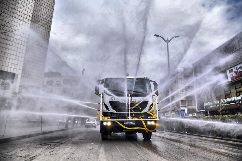 Syrian Red Crescent vehicles spraying disinfectant along a street in the capital Damascus. AFP