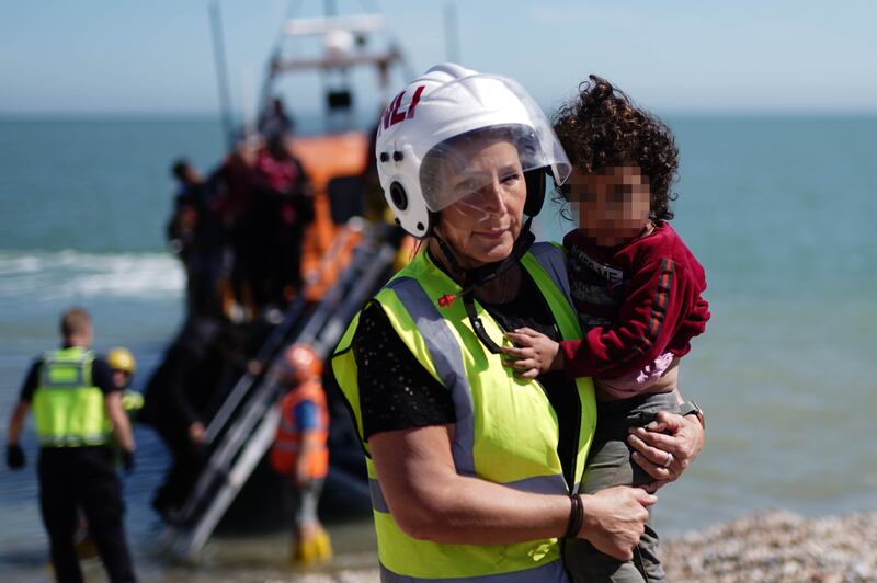 A migrant child is carried after arriving in Kent, following rescue from a small boat in the English Channel on August 16, 2023. PA