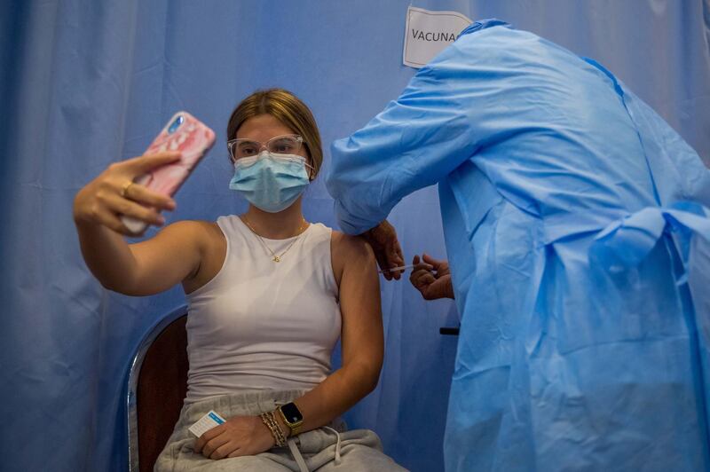 A woman takes a photo as she receives a dose of Covid-19 vaccine in Caracas, Venezuela. EPA