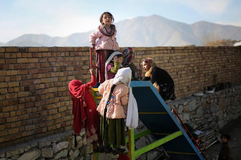 Young Afghan girls play on a slide at a camp for internally displaced people in Kabul, Afghanistan. AP Photo