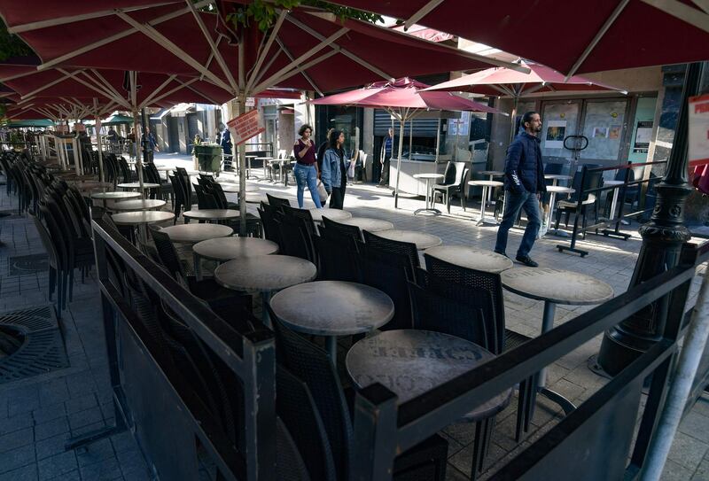 Pedestrians walk in front of a closed sidewalk cafe in the centre of the Tunisian capital Tunis after the government's decision to shut down bars, cafes and restaurants in a bid to limit the spread of the coronavirus Covid-19.  AFP