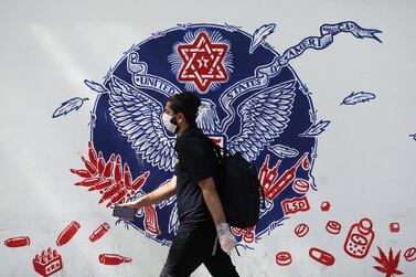 An Iranian man walks past a wall of a former US Embassy, following the outbreak of the coronavirus, in Tehran. West Asia News Agency