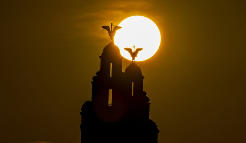 The summer solstice sun rises behind the Liver Building, in Liverpool, north-western England, silhouetting the mythical liver birds that are the symbol of the city. PA