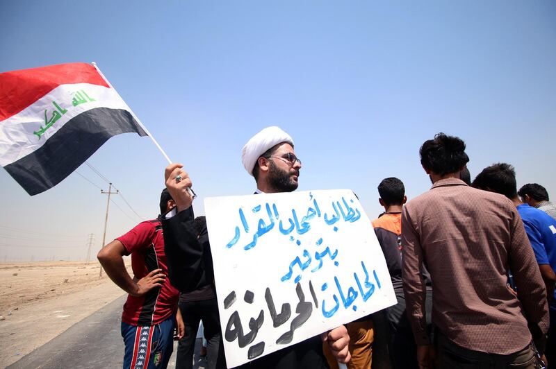 A protester holds a sign that reads "We ask the decision makers to provide the things we are deprived of" during a protest in south of Basra, Iraq July 16, 2018. REUTERS/Essam al-Sudani