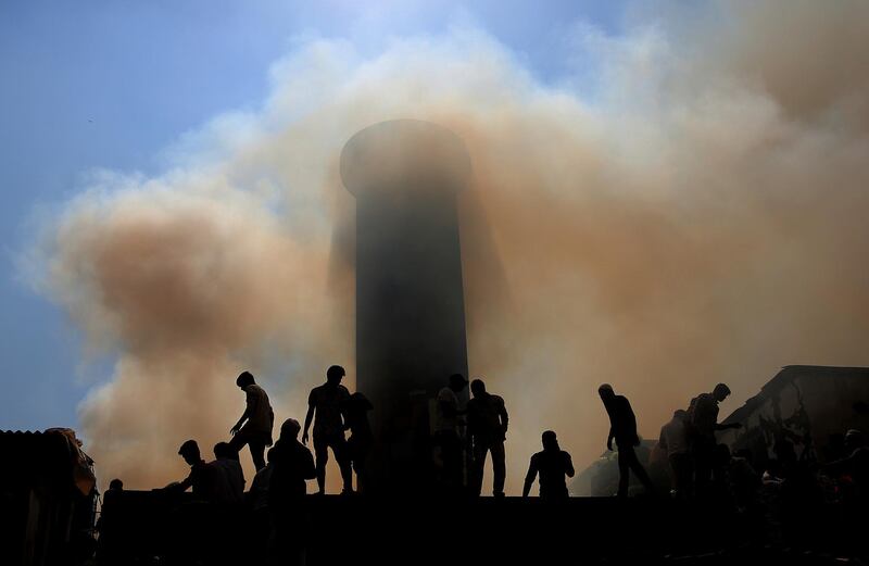 People are silhouetted against the smoke as firefighters try to douse the fire at a slum in Mumbai, India. AP Photo