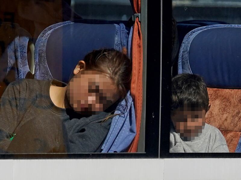 A group of people thought to be migrants, including children, are driven away from the Border Force compound in Dover, Kent. PA