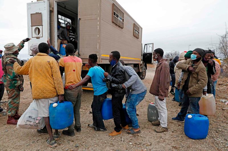 A South African National Defence Force  member directs suspected undocumented Zimbabwean nationals into a vehicle after attempting to illegally cross the border fence to smuggle goods and fuel into Zimbabwe from South Africa near the Beitbridge border post, near Musina. AFP