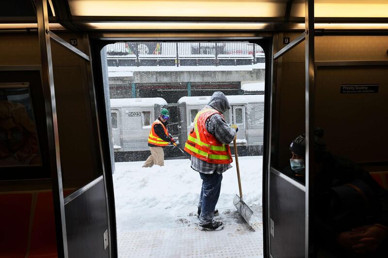 Workers clear snow off a subway station platform in Brooklyn. AFP