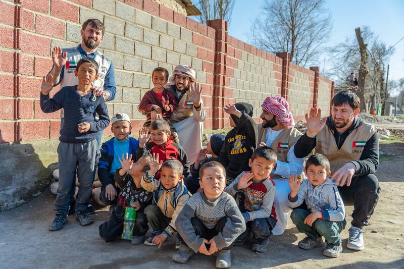 Children smile for the camera after getting their food boxes from the UAE.