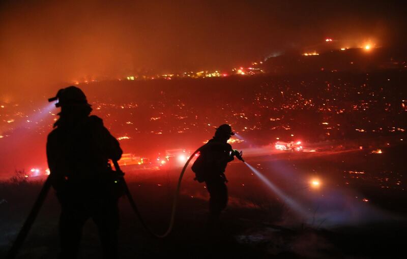 Firefighters walk to the fire line at the Lilac fire in Bonsall, California on December 7, 2017.
Local emergency officials warned of powerful winds on December 7 that will feed wildfires raging in Los Angeles, threatening multi-million dollar mansions with blazes that have already forced more than 200,000 people to flee.  / AFP PHOTO / Sandy Huffaker