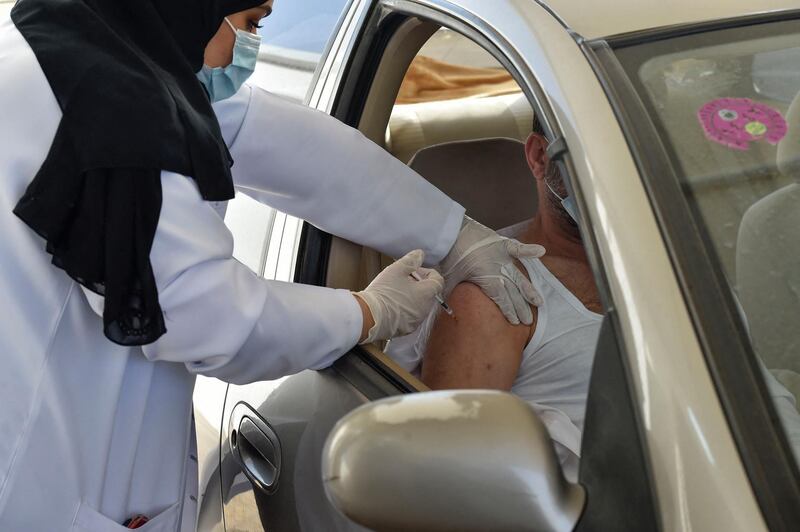 A medical worker administers a dose of the AstraZeneca COVID-19 vaccine at the first drive-through vaccination center in the Saudi capital Riyadh, on March 4, 2021. / AFP / Fayez Nureldine
