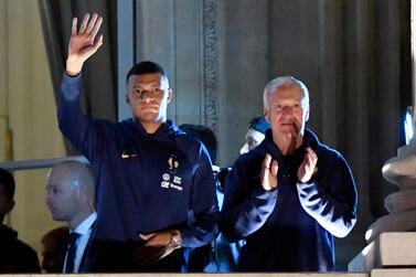 France's forward Kylian Mbappe (L) and France's coach Didier Deschamps (R) greet supporters at the Hotel de Crillon, a day after the Qatar 2022 World Cup final match against Argentina, at the Place de la Concorde in central Paris on December 19, 2022.  (Photo by JULIEN DE ROSA  /  AFP)