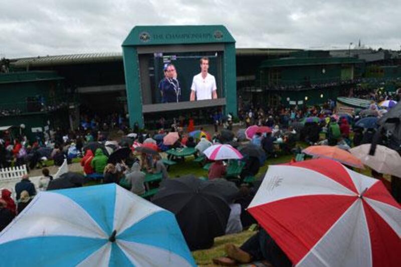 Spectators shelter from the rain under umbrellas on 'Murray Mound' while watching the fourth round men's singles match between Britain's Andy Murray and Croatia's Marin Cilic