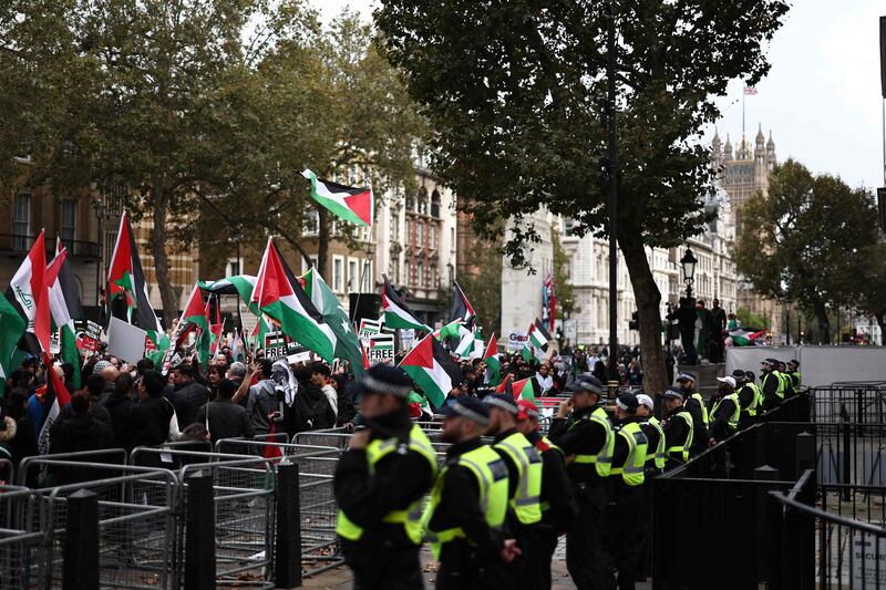 Police officers look on as protesters wave Palestinian flags at the gates of Downing Street. AFP