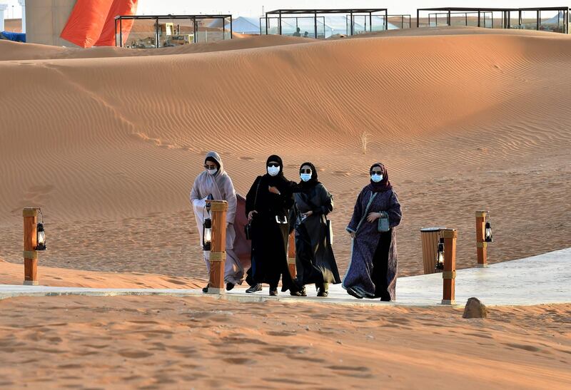 Women walk amid dunes at the "Riyadh Oasis." AFP