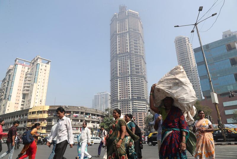 Indian walks past an under construction building in Mumbai, India, Tuesday, Jan. 21, 2020. The IMF on Monday lowered India's economic growth estimate for the current fiscal to 4.8% and listed the country's Gross Domestic Product (GDP) numbers as the single biggest drag on its global growth forecast for two years. (AP Photo/Rafiq Maqbool)