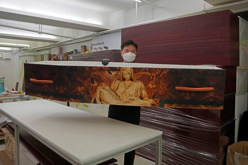 A worker lifts up a paper coffin at LifeArt's factory in Hong Kong. LifeArt says its alternative, cardboard coffins are environmentally friendly.