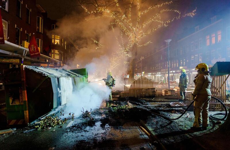TOPSHOT - Firefighters work to extinguish a fire on the Groene Hilledijk in Rotterdam, on January 25, 2021, after a second wave of riots in the Netherlands following the introduction of a coronavirus curfew over the weekend. Riot police clashed with groups of protesters in Amsterdam as well as the port city of Rotterdam, Amersfoort in the east, and the small southern city of Geleen near Maastricht, police and Dutch news reports said.
 - Netherlands OUT
 / AFP / ANP / Marco de Swart
