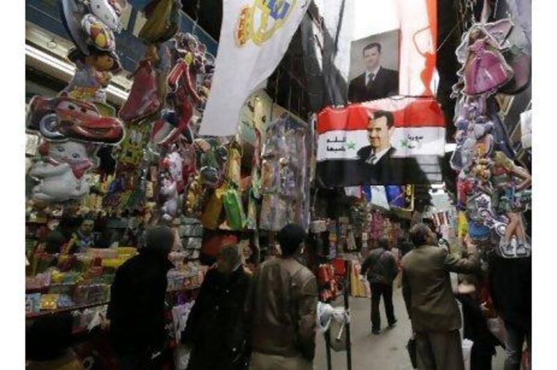 A portrait of the Syrian president Bashar Assad dominates a shopping alley in Damascus. A reader says that Syria has not experienced political unrest because the people genuinely like their president. Hussein Malla / AP
