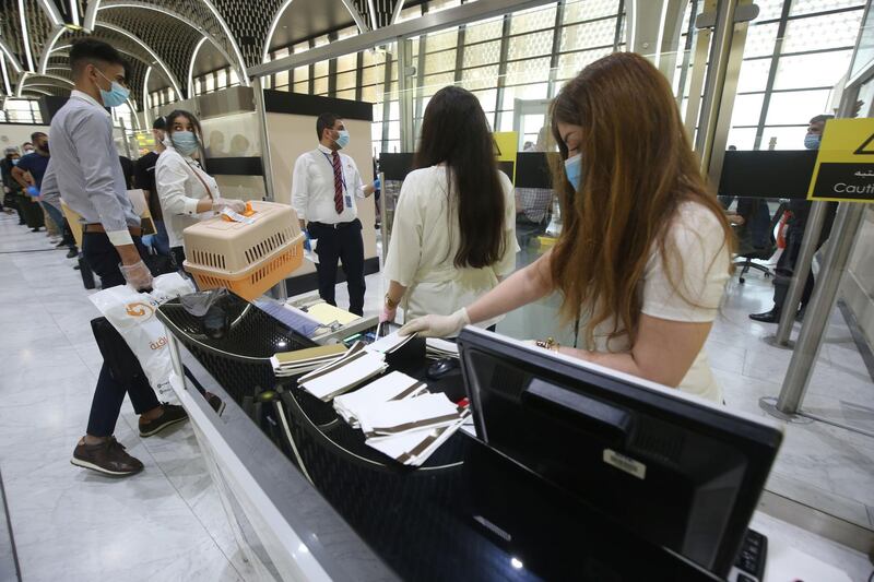 Passengers wearing protective masks leave the departure hall at Baghdad international airport to board a flight following the airport's reopening.  AFP