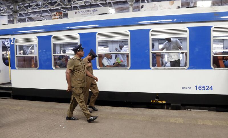 Security personnel walk past a passenger train at Fort train station in Colombo. EPA