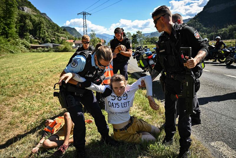 French gendarmes remove environmental protestors from the race route. AFP